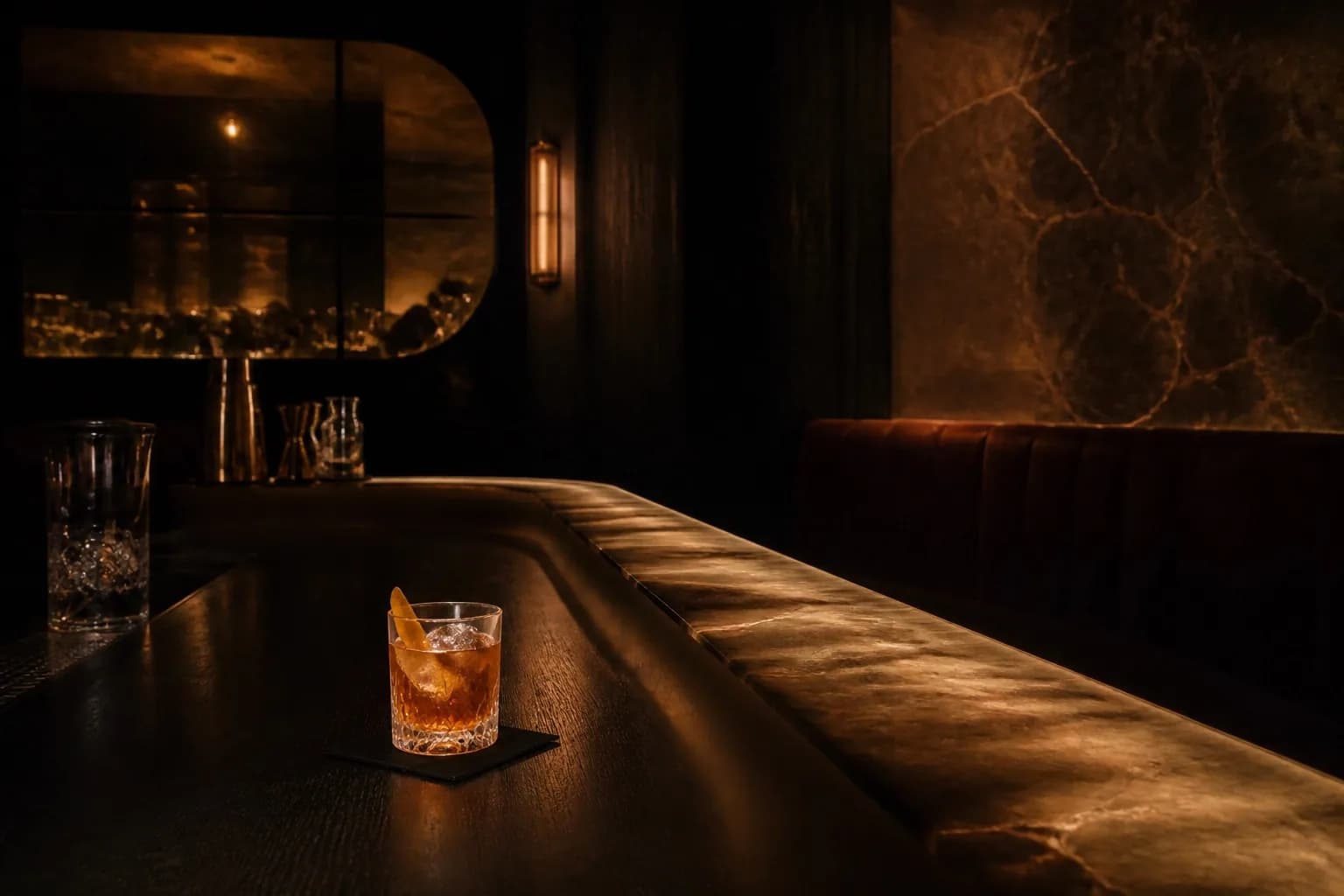 Bar sombre VANTA avec comptoir en pierre éclairé d'une lumière ambrée